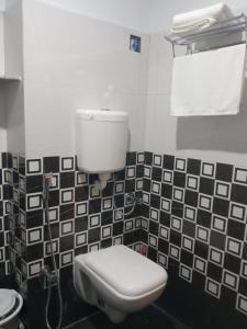 a bathroom with a toilet and black and white tiles at Soukyam Hotel in Kolkata
