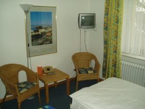 een kamer met een bed en twee stoelen en een televisie bij Hotel Friedrichs in Neumünster