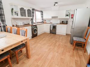 eine Küche mit Tisch und Kühlschrank in der Unterkunft Broombaulks Farm Bungalow in Jedburgh