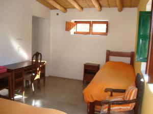 a bedroom with a bed and a desk and a table at Lo de Lili in Tilcara