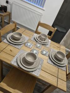 a wooden table with plates and dishes on it at Spacious and Modern Town House close to The Lake District in Barrow in Furness