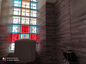 een glas-in-loodraam in een badkamer met een vuilnisbak bij Holiday rooms with private bathroom in Acilia
