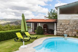 een zwembad met 2 stoelen en een parasol naast een huis bij Douro House Loft in Tabuaço