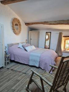 a bedroom with a bed and a chair and a mirror at Laronde Gites a Baragane in Taillant