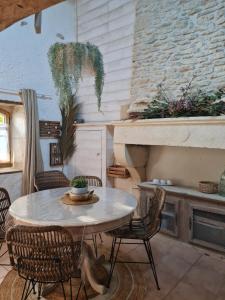 une table et des chaises dans une cuisine avec un mur en pierre dans l'établissement Laronde Gites a Baragane, à Taillant