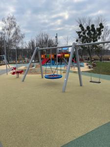 un parque infantil con columpios en ALOE Apartman, en Sárvár