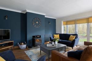 a living room with a couch and a clock on the wall at Draycott Farm in Chipping Campden