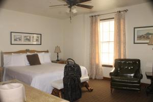 una camera con un letto e una sedia con una valigia di Boulder Dam Hotel a Boulder City