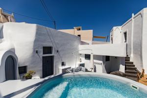 a swimming pool in front of a white house at Gemini Cave in Oia