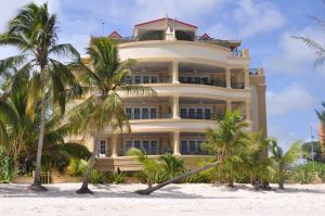 un gran edificio amarillo en la playa con palmeras en White Sands Beach Condos, en Christ Church