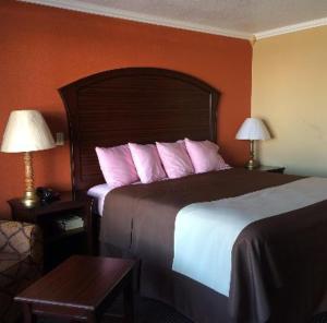 a hotel room with a large bed with pink pillows at Americas Best Value Inn Schulenburg in Schulenburg