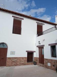 a white building with brown doors and windows at Casa cueva rural Vico ideal grandes grupos in Freila