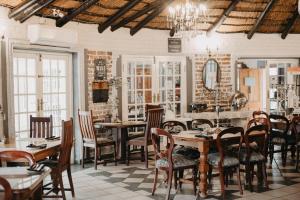 a dining room with tables and chairs and a chandelier at Arcadia 4star Guesthouse Kroonstad in Kroonstad
