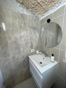 La salle de bains est pourvue d'un lavabo blanc et d'un miroir. dans l'établissement חצר הצ'אנס - בקתות להשראה, à Almog