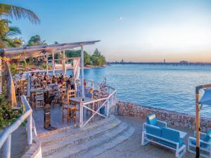 Coral Beach Hotel Dar Es Salaam في دار السلام: مجموعة اشخاص جالسين في مطعم بجانب الماء