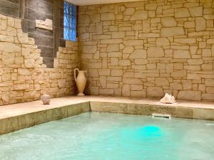 a large pool of water in a room with a stone wall at Le Château de la Roque Hôtels in Hébécrevon