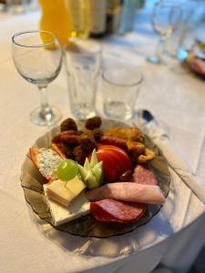 a plate of food on a table with wine glasses at house in the woods in Reşiţa