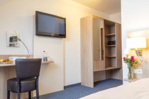 a hotel room with a television and a chair at Hotel Kelkheimer Hof in Kelkheim