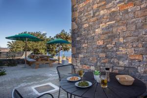 a wooden table with plates of food on a patio at Villa Nesea Elounda with private pool in Chavgas