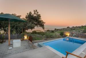 a swimming pool with an umbrella and a view of the ocean at Villa Nesea Elounda with private pool in Chavgas