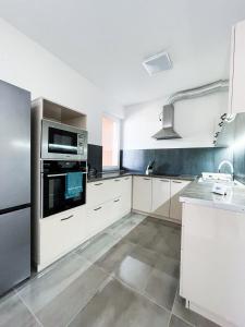 una cocina con armarios blancos y electrodomésticos de acero inoxidable en Villa Klapka, en Zamárdi