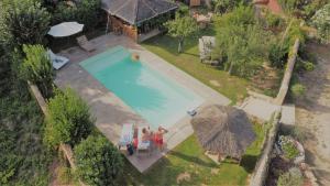 een uitzicht over een zwembad met twee personen en parasols bij La Closerie in Villeneuve-lès-Béziers