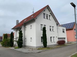a white house with a red roof and a street at Ferienwohnung Am Gießbach 15 in Bodman-Ludwigshafen