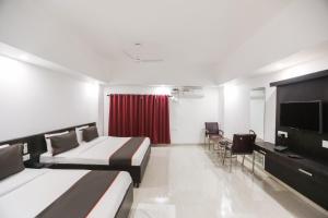 a hotel room with two beds and a flat screen tv at Collection O Hotel Belmorrise in Noida