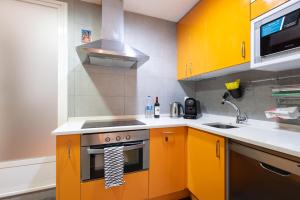 薩拉戈薩的住宿－Origen Sacramento Deluxe，厨房配有黄色橱柜和炉灶。