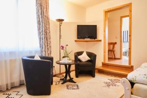 a living room with two chairs and a table and a television at Gasthof & Pension Steppacher in Friedenweiler