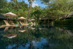 a swimming pool with umbrellas and chairs and trees at Khaolak Wanaburee Resort - SHA Extra Plus in Khao Lak
