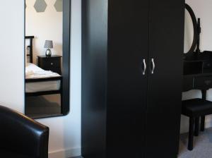a black cabinet with a mirror next to a bedroom at Abingdon - Private Flat with Garden & Parking 06 in Abingdon