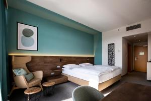 ロイパースドルフ・バイ・フュルステンフェルトにあるダス ソンライヒ - テルメンホテル ロイパースドルフのベッドと椅子付きのホテルルーム