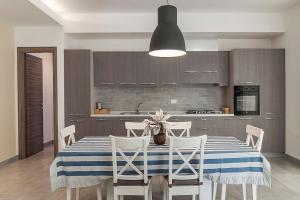 a kitchen with a table with white chairs and a kitchen with at Silvy House in Terracina