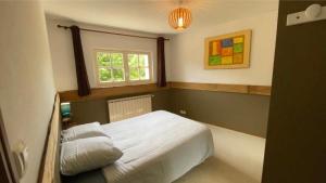 a bedroom with a white bed and a window at Appartement aux Sources de la Chabanne in Saint-Hilaire-les-Courbes