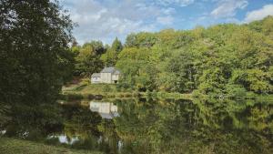 a house on a hill next to a lake at Appartement aux Sources de la Chabanne in Saint-Hilaire-les-Courbes