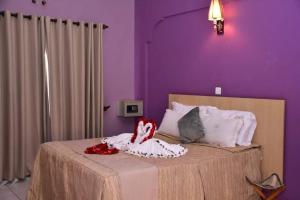 a purple bedroom with a bed with two dolls on it at Mpeta House in Nyeri