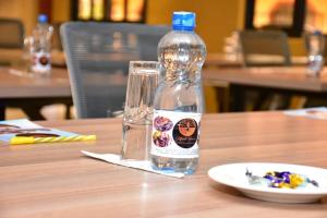 une bouteille d'eau assise sur une table à côté d'une assiette dans l'établissement Mpeta House, à Nyeri