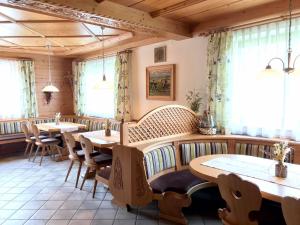 a restaurant with wooden tables and chairs and windows at Untergrundgut in Leogang