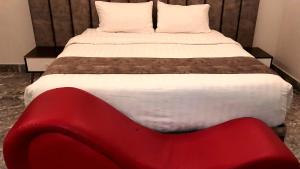 جولدن نيو جوان - Golden New Gewan Hotel في أبها: سرير مع كرسي احمر في الغرفة