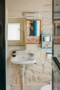 ein Badezimmer mit einem weißen Waschbecken und einem Spiegel in der Unterkunft The Stone House in Ägina Stadt + 42 Fotos
