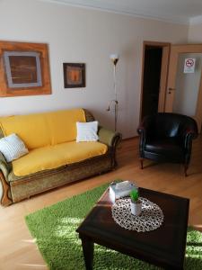 a living room with a yellow couch and a coffee table at Beatrix Apartments in Bük