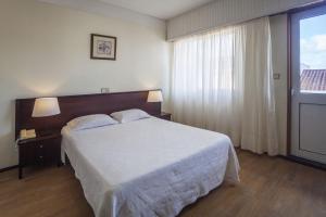 um quarto com uma grande cama branca e uma janela em Hotel Sete Cidades em Ponta Delgada