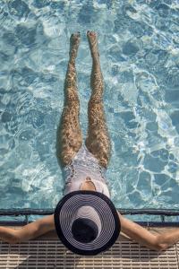 a person laying in a swimming pool with a hat at Hotel Pirchnerhof in Reith im Alpbachtal