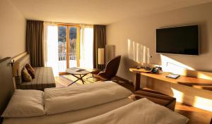 um quarto de hotel com uma cama e uma secretária com uma televisão em Hotel Saratz Pontresina em Pontresina