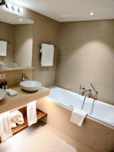 a bathroom with a tub and a sink and a mirror at Hotel Saratz Pontresina in Pontresina