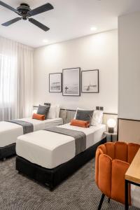 a bedroom with two beds and a chair at The New Port Hotel TLV in Tel Aviv
