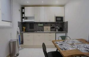 a kitchen with white cabinets and a table with chairs at Superbe appartement cosy in Saint-Ouen