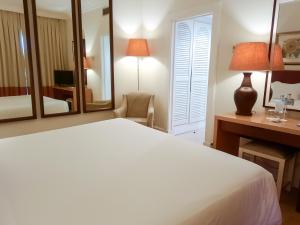 a bedroom with a bed and a desk and a mirror at Azoris Faial Garden – Resort Hotel in Horta