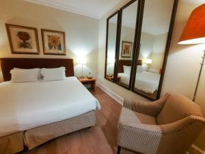 a bedroom with a bed and a mirror and a chair at Azoris Faial Garden – Resort Hotel in Horta